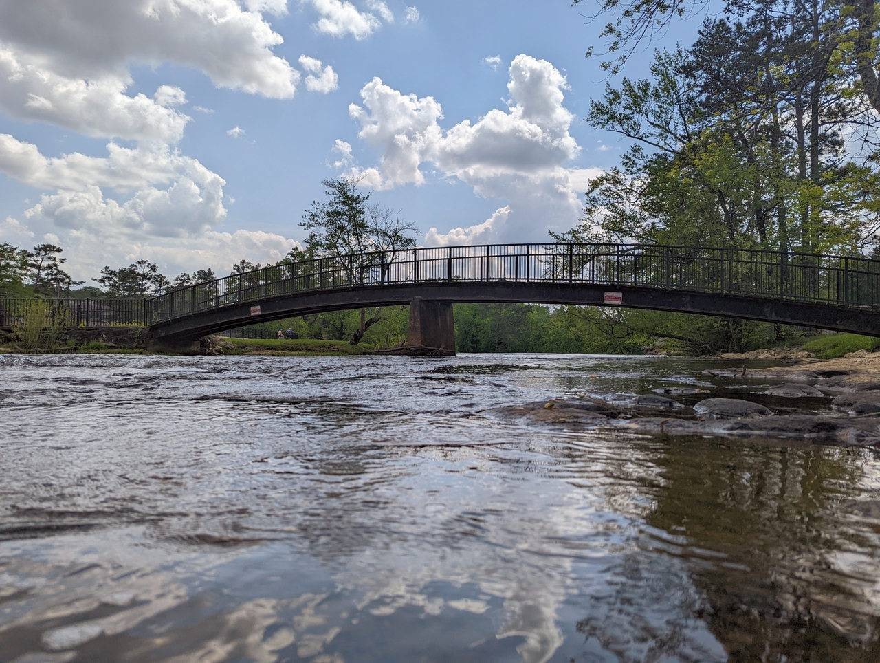 Bridge over a calm river under a partly cloudy sky.